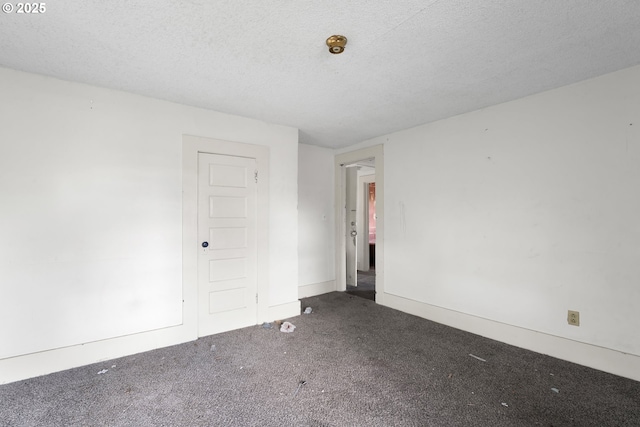 carpeted empty room featuring a textured ceiling and baseboards