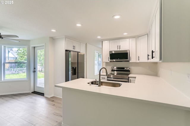 kitchen with a sink, appliances with stainless steel finishes, a peninsula, and light countertops