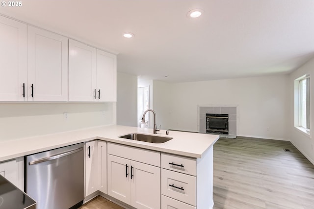 kitchen featuring a sink, light countertops, a peninsula, white cabinetry, and stainless steel dishwasher