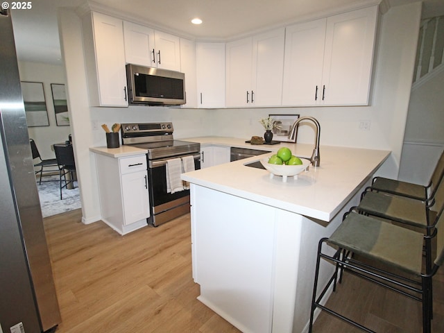 16400 NE 12th St, Vancouver, WA 98684 - kitchen featuring stainless steel appliances, a peninsula, light wood-style floors, white cabinetry, and a breakfast bar