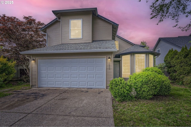 traditional-style home featuring concrete driveway, roof with shingles, and a garage