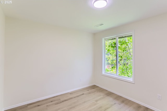 spare room featuring visible vents, light wood-style flooring, and baseboards