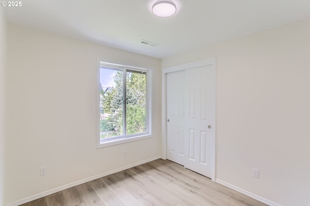unfurnished bedroom featuring baseboards, visible vents, light wood finished floors, and a closet