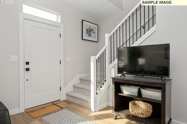 entryway featuring stairway, baseboards, and wood finished floors