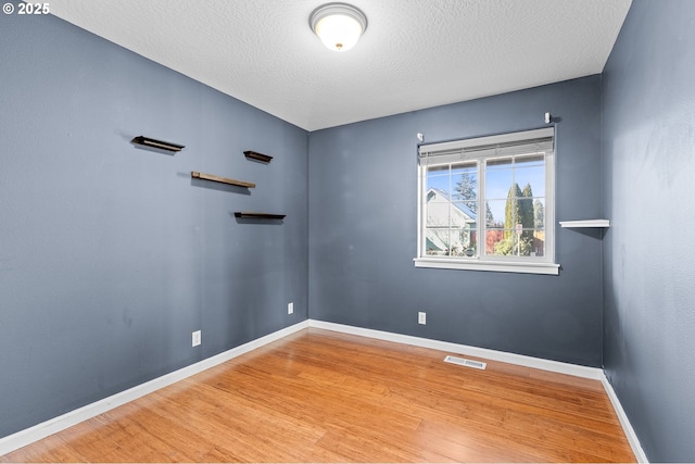 unfurnished room featuring wood-type flooring and a textured ceiling