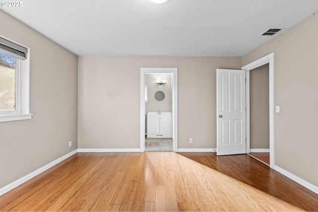 unfurnished bedroom featuring ensuite bath and light hardwood / wood-style flooring