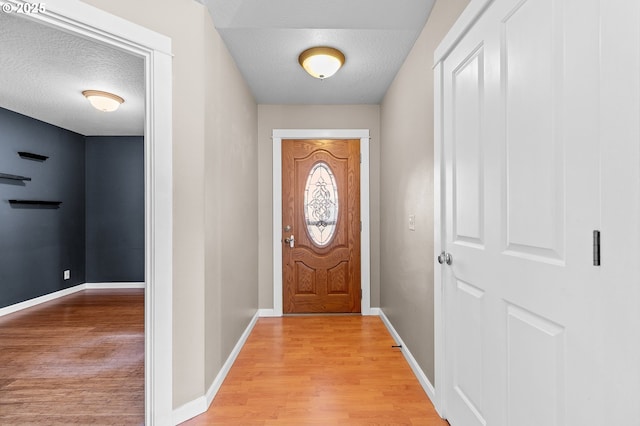 doorway featuring a textured ceiling and light hardwood / wood-style floors