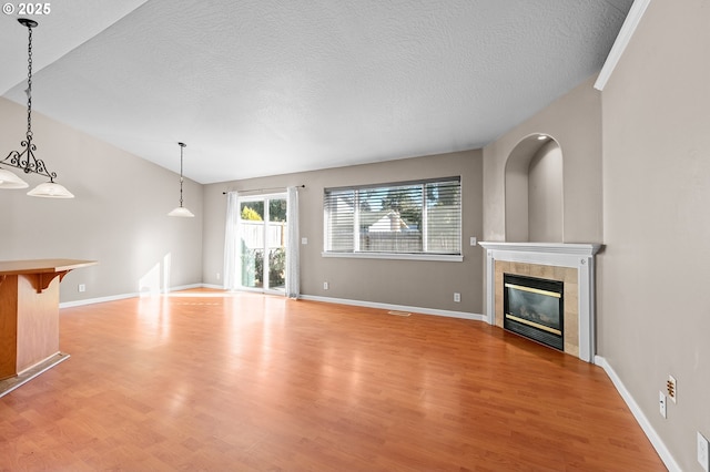 unfurnished living room featuring a tiled fireplace, a textured ceiling, and light hardwood / wood-style flooring