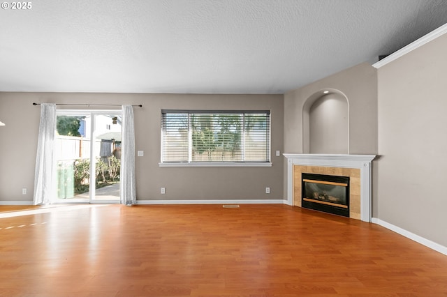 unfurnished living room with hardwood / wood-style floors, a tile fireplace, and a textured ceiling