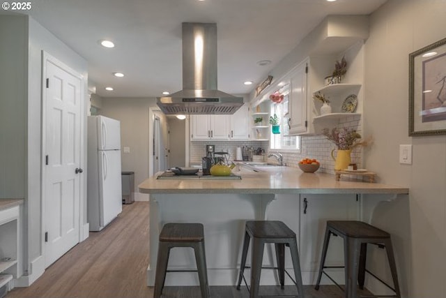 3681 Silverstone Ct NE, Salem, OR 97305 - kitchen with backsplash, island range hood, open shelves, freestanding refrigerator, and a peninsula