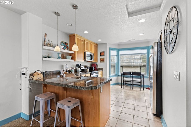 260 N Pacific St, Rockaway Beach, OR 97136 - kitchen featuring stainless steel appliances, a sink, baseboards, a peninsula, and a textured ceiling