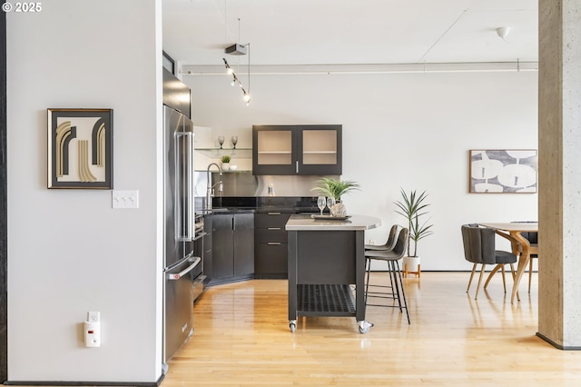 333 NW 9th Ave Unit 713, Portland, OR 97209 - kitchen with a sink, a breakfast bar area, light wood-style floors, glass insert cabinets, and high end refrigerator
