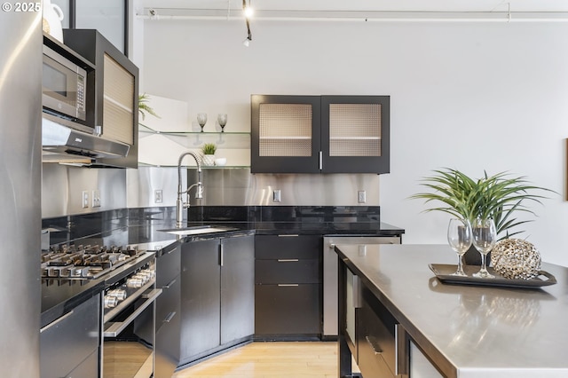 333 NW 9th Ave Unit 713, Portland, OR 97209 - kitchen featuring a sink, light wood finished floors, open shelves, appliances with stainless steel finishes, and glass insert cabinets