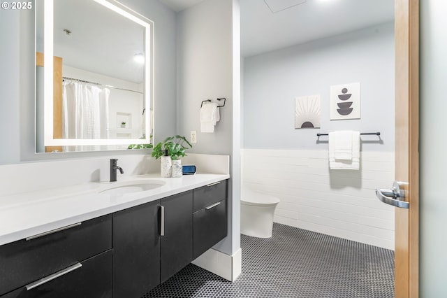 333 NW 9th Ave Unit 713, Portland, OR 97209 - full bath featuring toilet, vanity, a wainscoted wall, tile patterned flooring, and tile walls