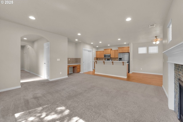3015 Guadalupe Way, Eugene, OR 97408 - unfurnished living room with light carpet, a tiled fireplace, baseboards, recessed lighting, and arched walkways