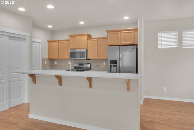 3015 Guadalupe Way, Eugene, OR 97408 - kitchen featuring appliances with stainless steel finishes, light wood-style flooring, light countertops, a kitchen bar, and baseboards