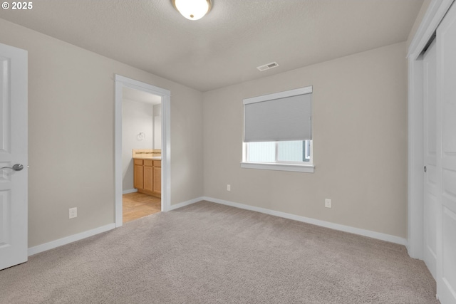 3015 Guadalupe Way, Eugene, OR 97408 - unfurnished bedroom featuring light colored carpet, a closet, baseboards, connected bathroom, and a textured ceiling