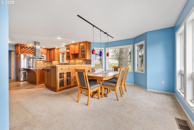 dining area with light colored carpet and track lighting