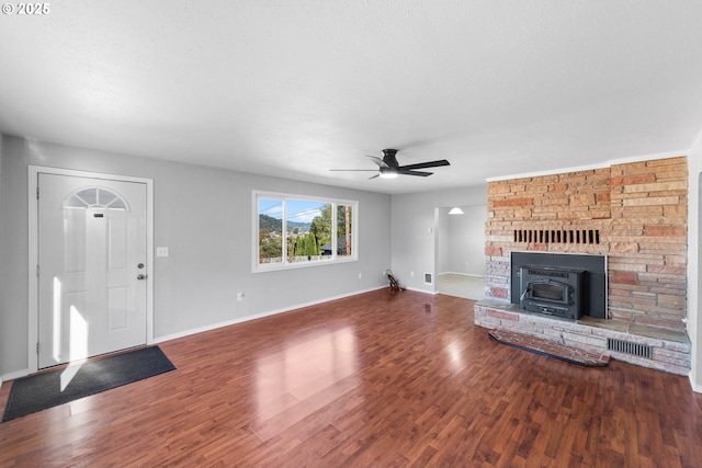 unfurnished living room with ceiling fan, wood-type flooring, and a wood stove