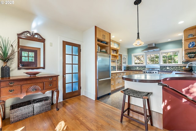 2783 NE Wiberg Ln, Portland, OR 97213 - kitchen featuring stainless steel refrigerator, open shelves, wall chimney range hood, backsplash, and hanging light fixtures
