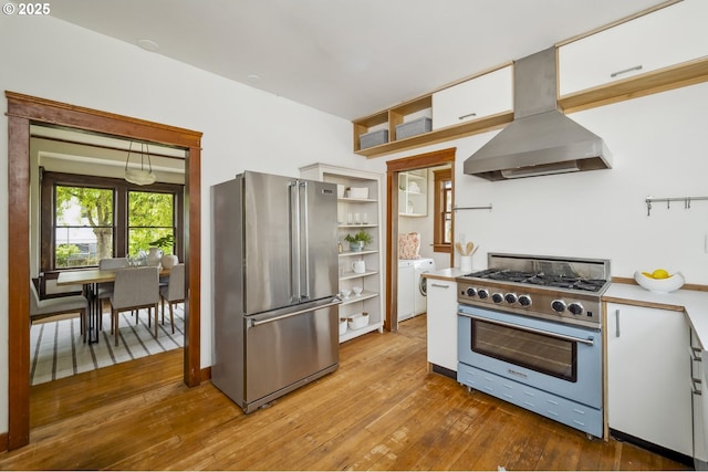 4919 NE 18th Ave, Portland, OR 97211 - kitchen featuring high end appliances, wall chimney range hood, washer and clothes dryer, hardwood / wood-style floors, and open shelves