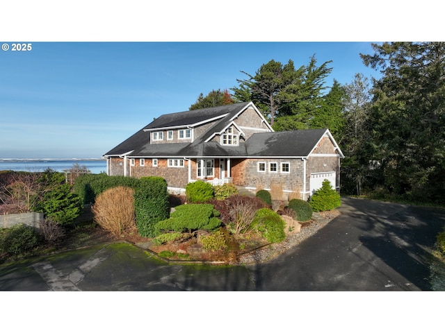 view of front facade with an attached garage, a water view, and aphalt driveway