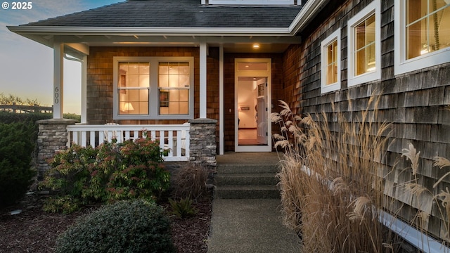 property entrance featuring a shingled roof and a porch