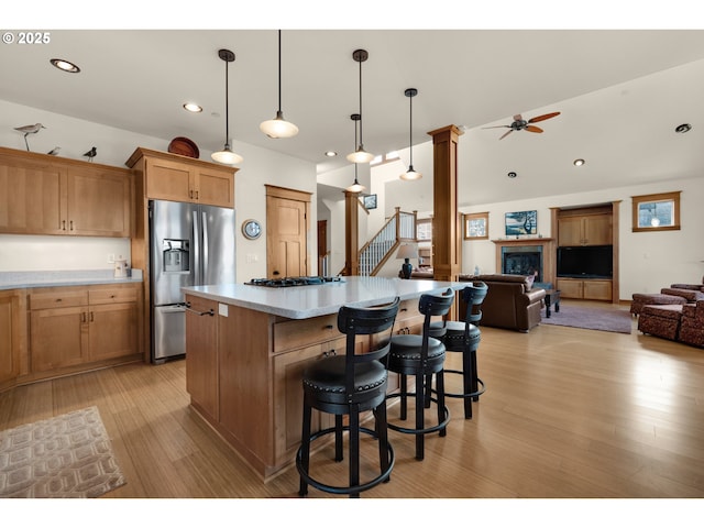 kitchen with open floor plan, ceiling fan, light wood-type flooring, light countertops, and stainless steel fridge with ice dispenser