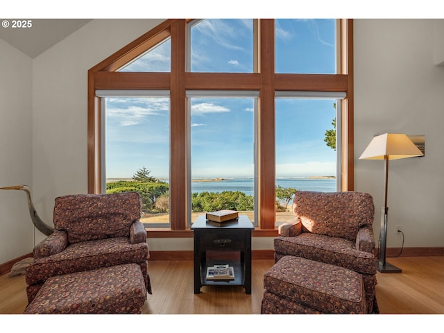 sitting room featuring a water view, baseboards, and wood finished floors
