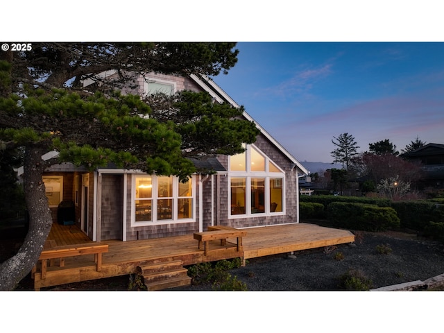 back of house at dusk featuring a wooden deck