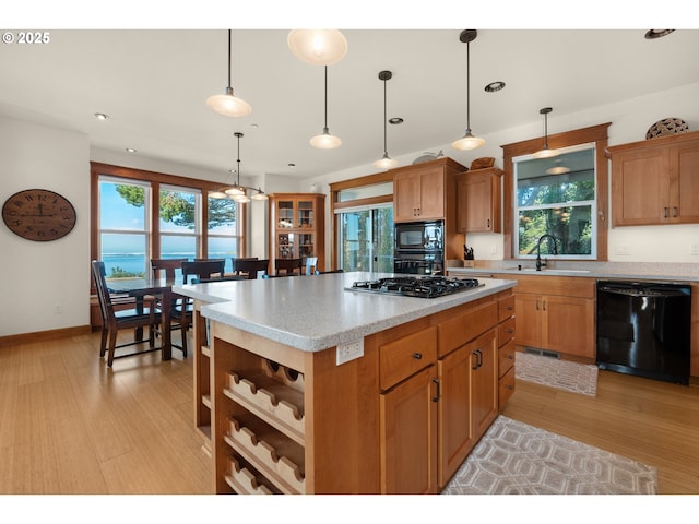 kitchen with a wealth of natural light, a sink, black appliances, and light wood-style floors