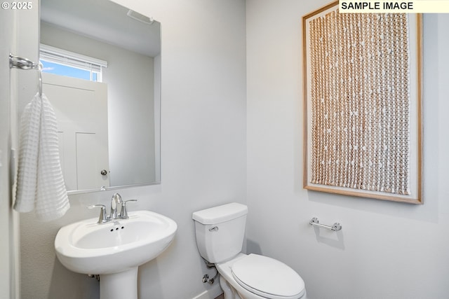half bath with toilet, baseboards, and a sink