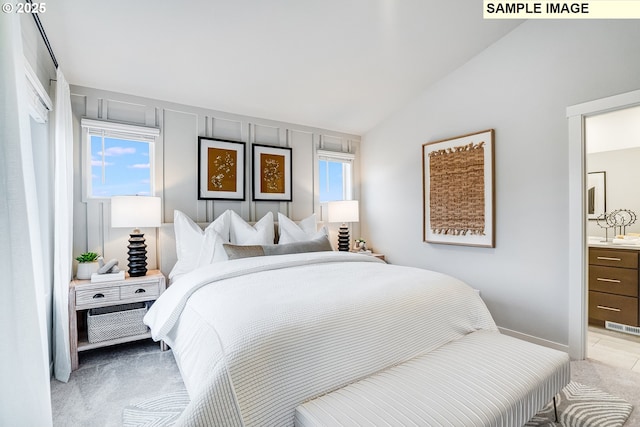 bedroom featuring vaulted ceiling, light colored carpet, and ensuite bathroom