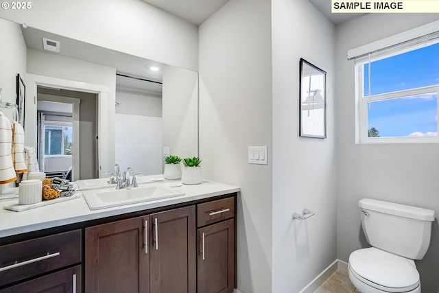 bathroom with toilet, vanity, and baseboards