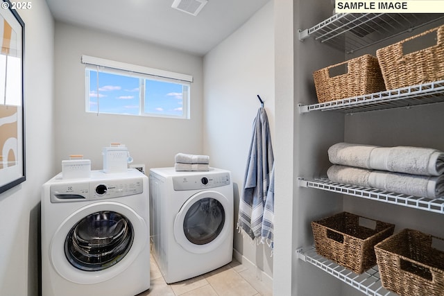 laundry area with independent washer and dryer, light tile patterned floors, and baseboards