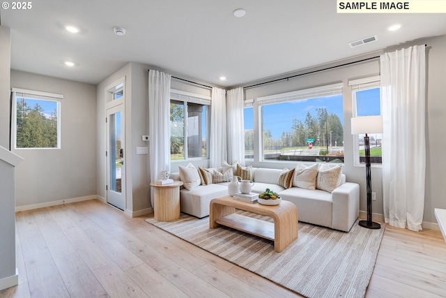 living room with baseboards, light wood finished floors, and recessed lighting