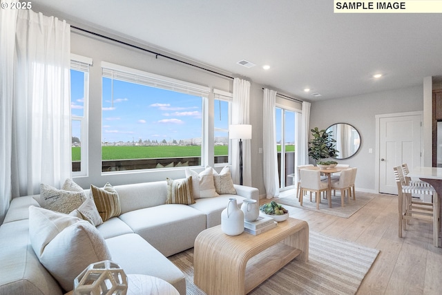 living area featuring recessed lighting, healthy amount of natural light, light wood-type flooring, and baseboards