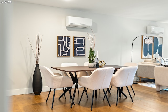 dining area with light wood finished floors, baseboards, and a wall mounted air conditioner