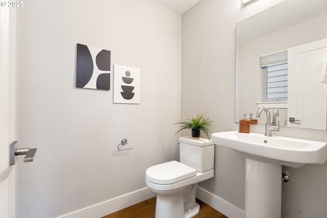 half bathroom with toilet, baseboards, and wood finished floors