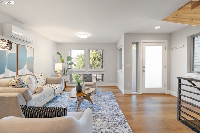 living room featuring recessed lighting, light wood-style flooring, baseboards, and a wall unit AC