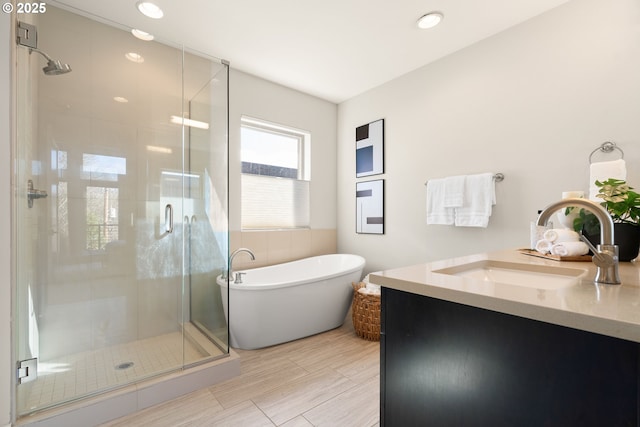 bathroom with a freestanding tub, a stall shower, and vanity