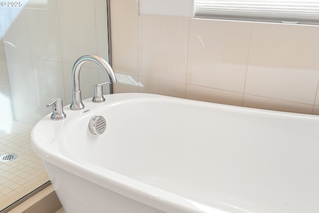 bathroom featuring tile walls and a freestanding tub