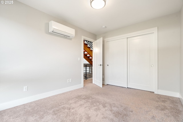 unfurnished bedroom with a closet, carpet flooring, a wall mounted AC, and baseboards