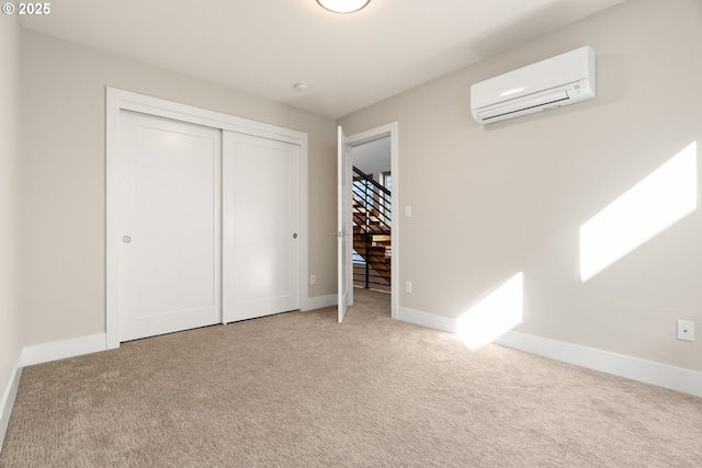 unfurnished bedroom featuring carpet flooring, baseboards, a closet, and a wall mounted AC