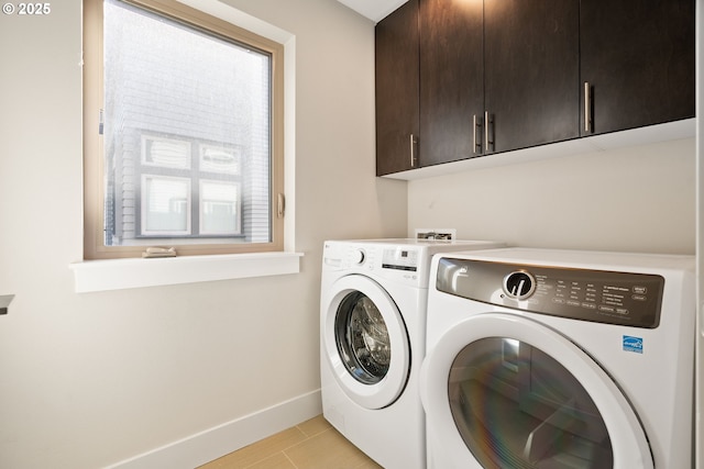 laundry area featuring separate washer and dryer, cabinet space, and baseboards