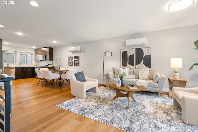 living area featuring recessed lighting, an AC wall unit, and light wood-style floors