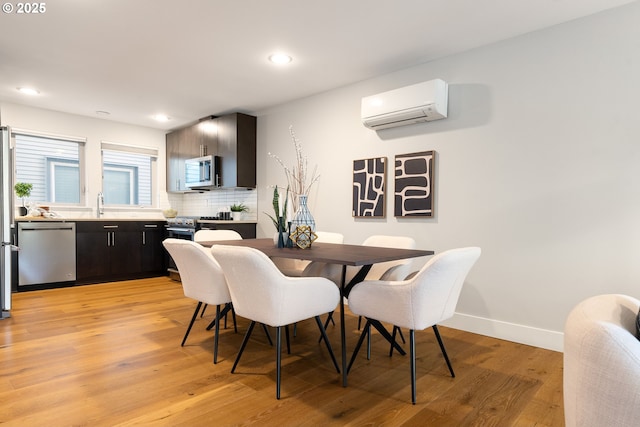 dining space with recessed lighting, light wood-style flooring, a wall mounted air conditioner, and baseboards