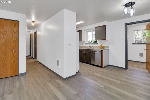 70 Jefferson Aly, Eugene, OR 97402 - kitchen featuring stainless steel dishwasher, a sink, light wood-style flooring, baseboards, and a textured ceiling