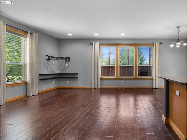 unfurnished living room featuring dark wood-type flooring, baseboards, plenty of natural light, and recessed lighting