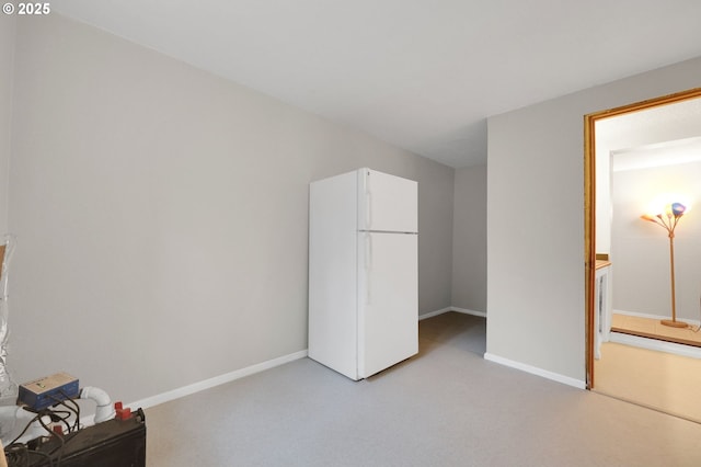 unfurnished bedroom with light colored carpet and white fridge